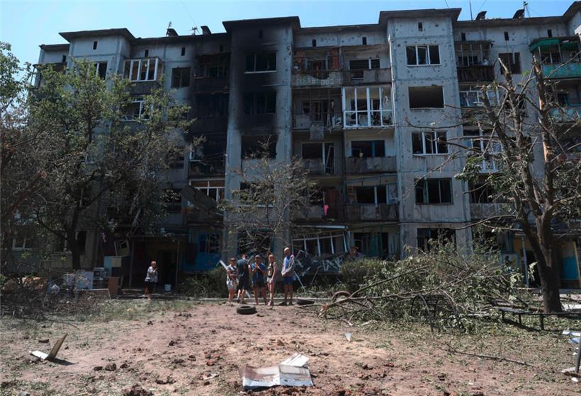 Bewohner stehen vor ihrem durch einen russischen Angriff beschädigten Wohnhaus in der ukrainischen Stadt Bachmut im Oblast Donezk
