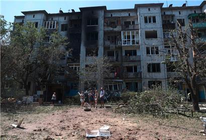 Bewohner stehen vor ihrem durch einen russischen Angriff beschädigten Wohnhaus in der ukrainischen Stadt Bachmut im Oblast Donezk
