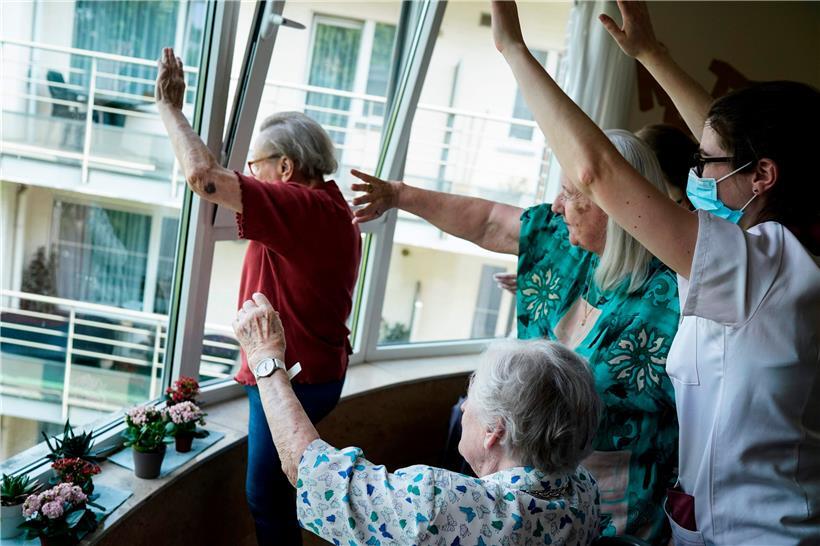 Bewohner und Pfleger eines Seniorenheims in Brüssel winken ihren Familien zu
