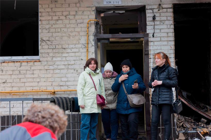 Bewohnerinnen stehen vor ihrem durch einen russischen Drohnenangriff stark beschädigten Wohnhaus in Kiew
