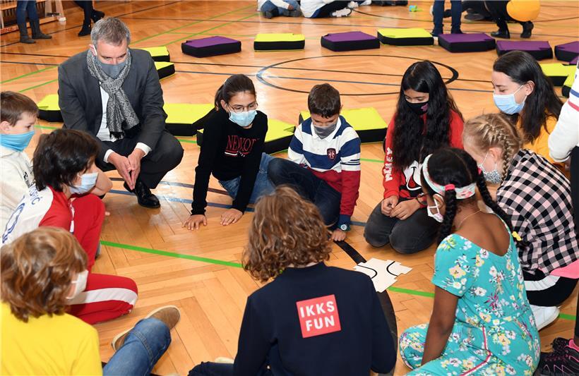 Bildungsminister Claude Meisch schaut sich in einer Schülergruppe an, wie die Kinder den Roboter Botly einprogrammieren
