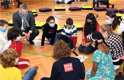 Bildungsminister Claude Meisch schaut sich in einer Schülergruppe an, wie die Kinder den Roboter Botly einprogrammieren

