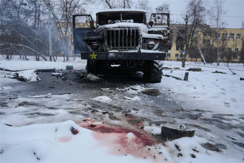 Blut von der Leiche eines Soldaten ist im Schnee neben einem zerstörten russischen Militärfahrzeug mit Mehrfachraketenwerfern am Stadtrand von Charkiw zu sehen

