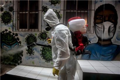 Brasilien, Rio de Janeiro: Ein Freiwilliger sprüht in einer Gasse im Slum Santa Marta Desinfektionsmittel, um die weitere Ausbreitung der Corona-Pandemie einzudämmen
