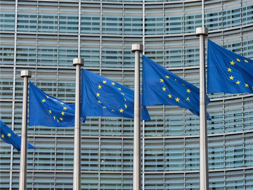 Mehrere wehende EU-Fahnen vor dem Gebäude der Europäischen Kommission in Brüssel bei klarem Himmel
