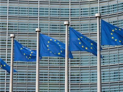 Mehrere wehende EU-Fahnen vor dem Gebäude der Europäischen Kommission in Brüssel bei klarem Himmel