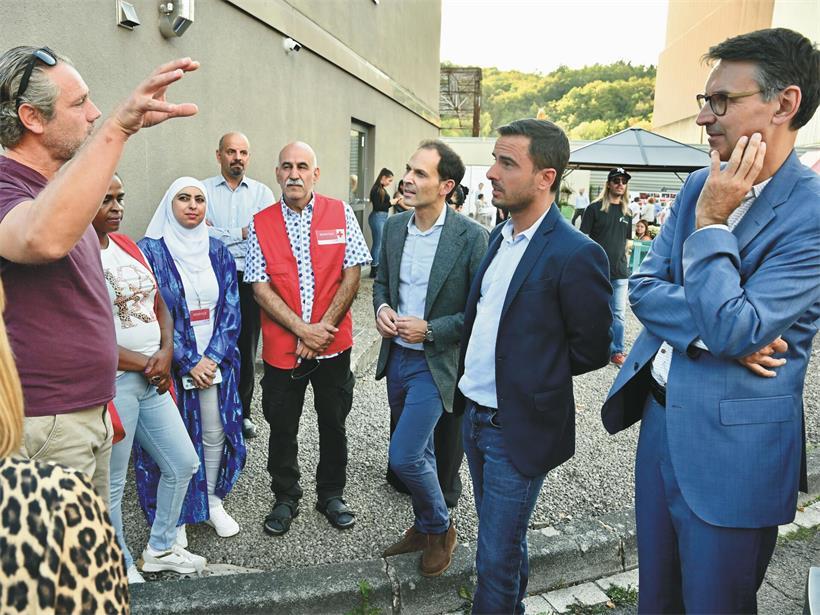 Düdelingens Flüchtlingsunterkunft feiert 10-jähriges Jubiläum Bürgermeister Dan Biancalana, Marc Wagener, Max Hahn und Ehrenamtliche im Gespräch beim Jubiläumsfest