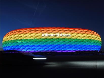 Bunte Bayern-Fans jubeln im Stadion mit Trikots und Fahnen bei Fußballspiel