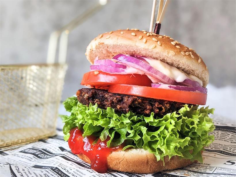 Burger auf einem rustikalen Holzbrett, Symbol für unveränderte Lebensmittelnamen trotz künftiger Änderungen bei anderen Produkten