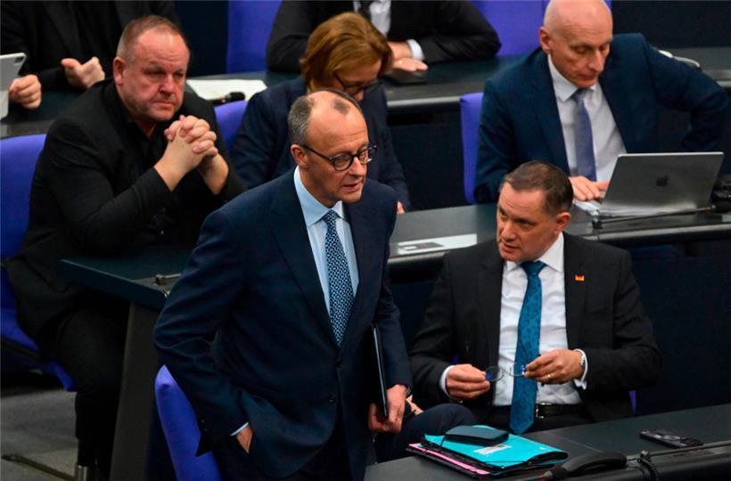 CDU-Chef Friedrich Merz (M.) schreitet im Bundestag an den rechtsextremen AfD-Abgeordneten – die ihm später zu einer Mehrheit für seinen Gesetzesvorschlag verhelfen – vorbei zum Rednerpult
