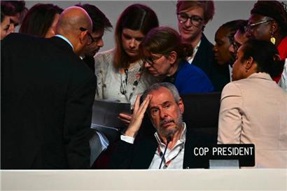 COP30-Präsident André Corrêa do Lago sieht illusionslos in den Saal, während hinter ihm Delegierte weiter verhandeln
