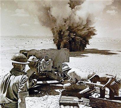 Campagne d’Afrique du Nord. Un obus ennemi atterrit près d’un canon pendant l’un des duels d’artillerie à longue distance qui font partie intégrante de la guerre dans le désert.
