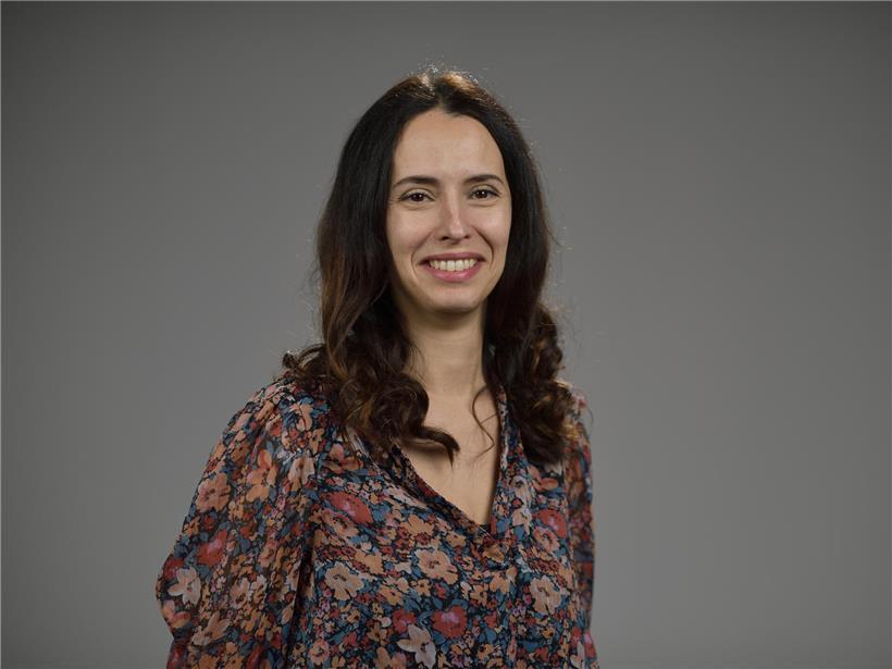 Porträtfoto von Carla Carvalho, lächelnd vor neutralem Hintergrund