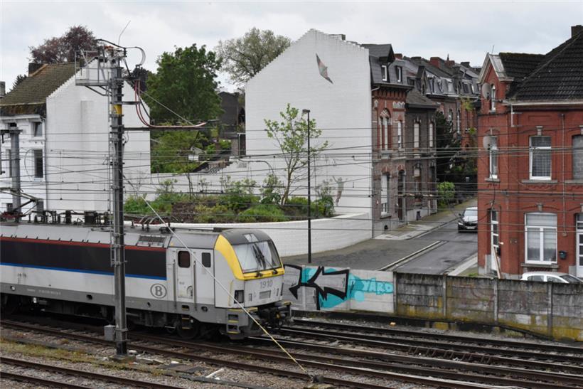 Charleroi, Mai 2024: Ein Lenkdrachen ist auf eine weiße Hauswand aufgemalt. Ein Gedenkgarten hinter Bahngleisen soll an die schrecklichen Taten im „Haus des Schreckens“ erinnern. An der Stelle stand eines der beiden Häuser, in denen Dutroux seine Verbrechen beging.
