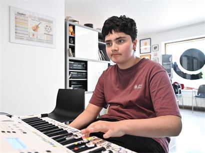 Clement beim Musikunterricht in Zolwer, lernend Gitarre zu spielen in einem hellen Klassenraum