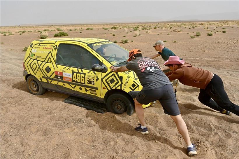 Menschen schieben gemeinsam ein Auto auf einer Straße, symbolisch für Teamarbeit und Hoffnung in schwierigen Situationen
