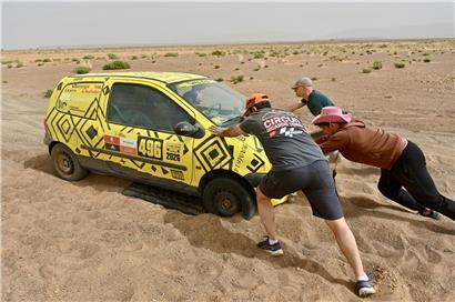 Menschen schieben gemeinsam ein Auto auf einer Straße, symbolisch für Teamarbeit und Hoffnung in schwierigen Situationen