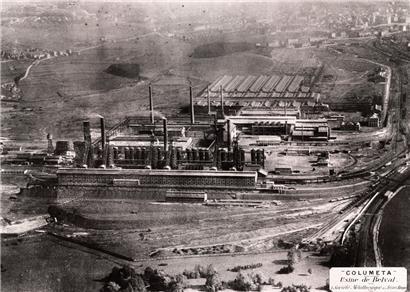 Das Belvaler Hüttenwerk nach der Übernahme durch die „Société métallurgique des Terres-Rouges“: vorne die erste Möllerei, dann die sechs Hochöfen von 1911/12 mit Cowpers, dahinter links die Gebläsehalle von 1913, rechts das Stahlwerk und im Hintergrund die Walzwerke sowie Teile der Stadt Esch. Foto von 1921. 
