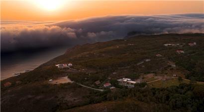 Das Bild zeigt eine seltene „Rollwolke“, eine riesige horizontale Wolke, die sich während der Hitzewelle in der Nähe von Cabo da Roca vom Horizont in Richtung der Strände des Atlantischen Ozeans bewegt
