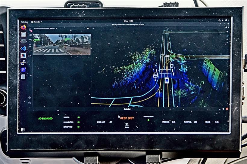 Das Display im Auto zeigt das dem System bekannte Kartenwerk (mit der „Schiene“ in der Straßenmitte) sowie die durch die Sensoren dynamisch erkannten Elemente. Besonders wichtig sind natürlich die anderen Verkehrsteilnehmer (die hier als weiße Gitterboxen erscheinen).
