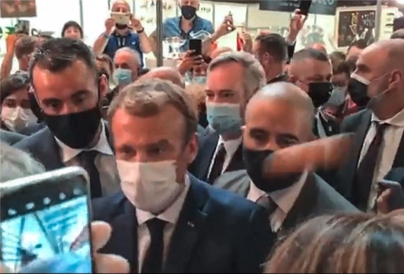 Das Ei trifft Macron rechts am Kopf – zerbersten tut es aber nicht
