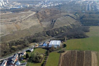 Das Foto zeigt den Erdrutsch 2014. Grund für die Instabilität des Geländes ist Wasser, wie anschließende Studien belegen. Die Erdmassen zerstörten damals die Verbindungsstraße zwischen Monnerich und der Stadt Esch. Mittlerweile gibt es wieder eine Straße (CR 106), sie wurde neben der alten neu gebaut.
