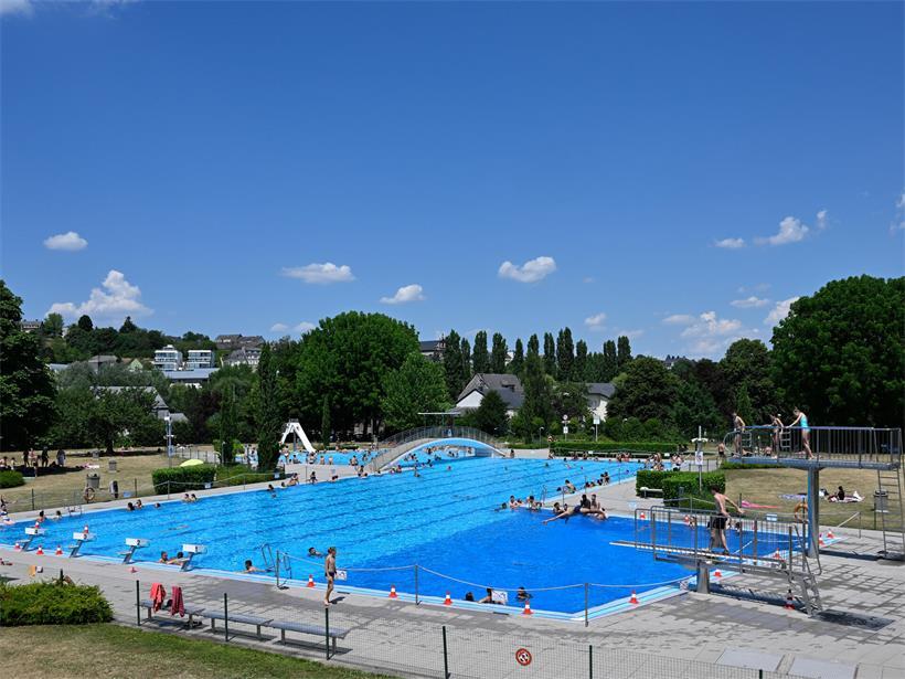 Freibad Remich mit Brücke, Sprungbrett, Wasserrutsche und mehreren Schwimmbecken an sonnigem Tag