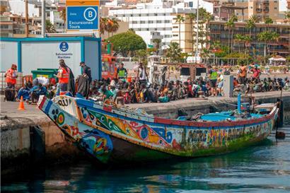 Das Holzboot liegt angetaut im Hafen von Los Cristianos, nur wenige hundert Meter entfernt sonnen sich Tausende von Touristen am Strand
