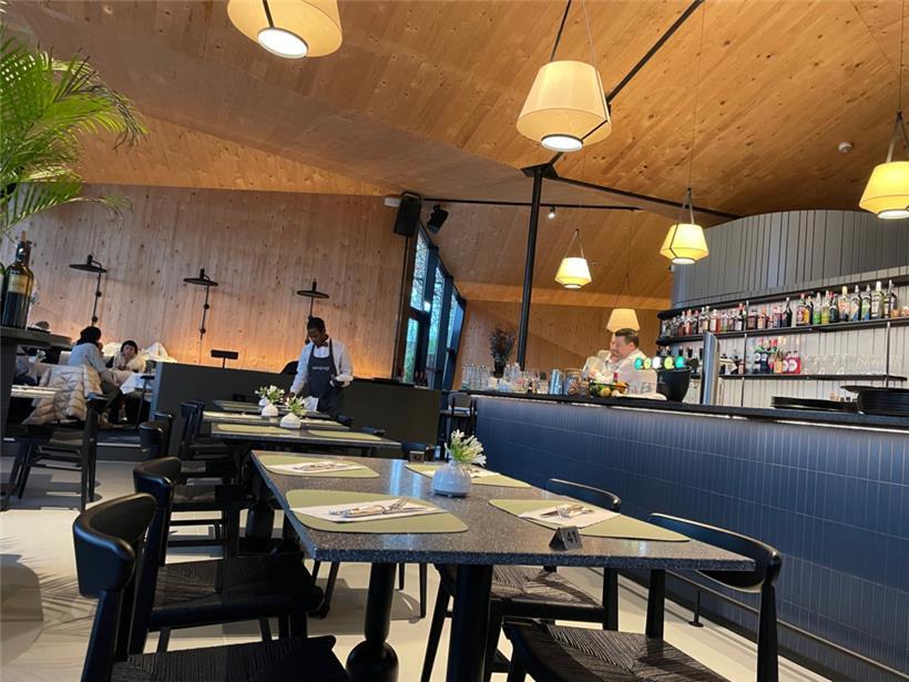 Das Innendesign kombiniert warme Holzelemente mit poliertem Beton und einem markanten blauen Fliesen-Counter
