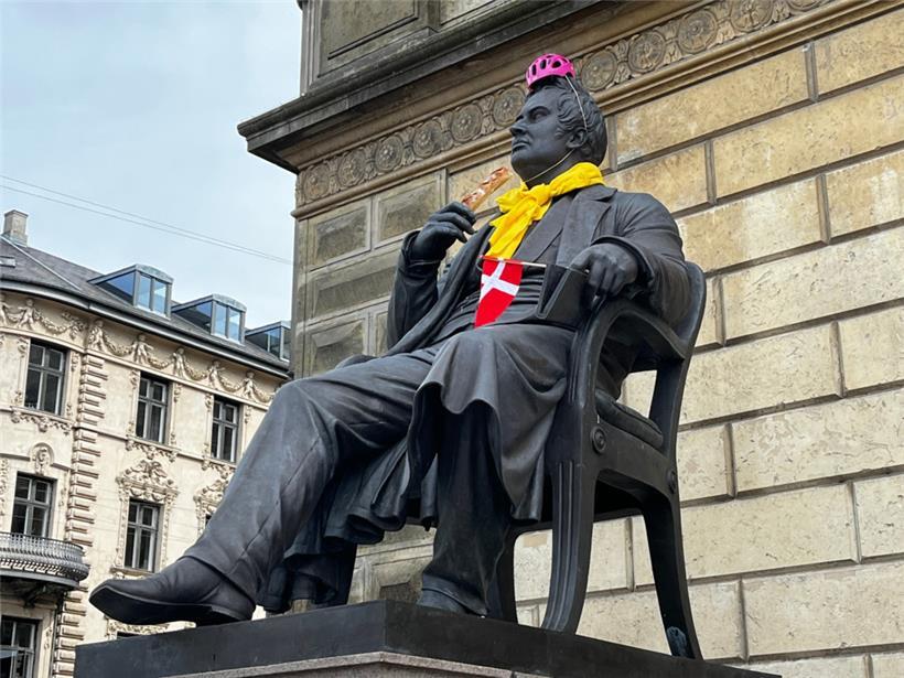 Das Monument von Dänemarks Nationaldichter Adam Gottlob Oehlenschläger mit rosa Helm, „Maillot jaune“, dänischer Flagge und französischem Baguette
