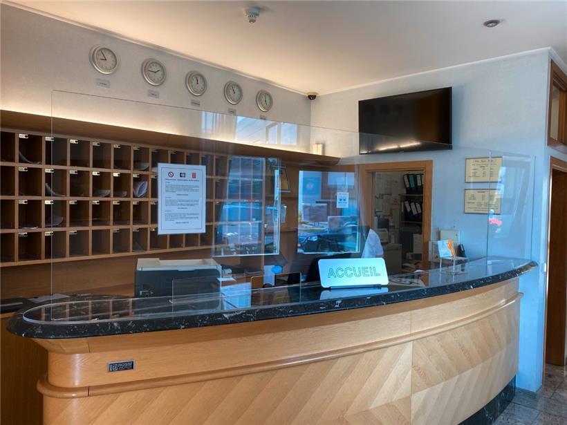 Das Personal im Empfang des Hotels wird durch eine Plexiglaswand geschützt