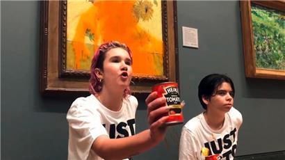 Das von Just Stop Oil herausgegebene Foto zeigt zwei Demonstrantinnen, von denen eine eine Dose Tomatensuppe hält, die Vincent Van Goghs berühmtes Werk „Sonnenblumen“ von 1888 in der National Gallery in London mit Dosensuppe beworfen haben. 
