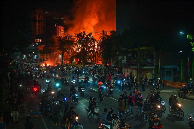 Demonstranten fahren mit Motorrädern vor einem Polizeihauptquartier vorbei, das während der Proteste in Surabaya am 31. August niedergebrannt und geplündert wurde
