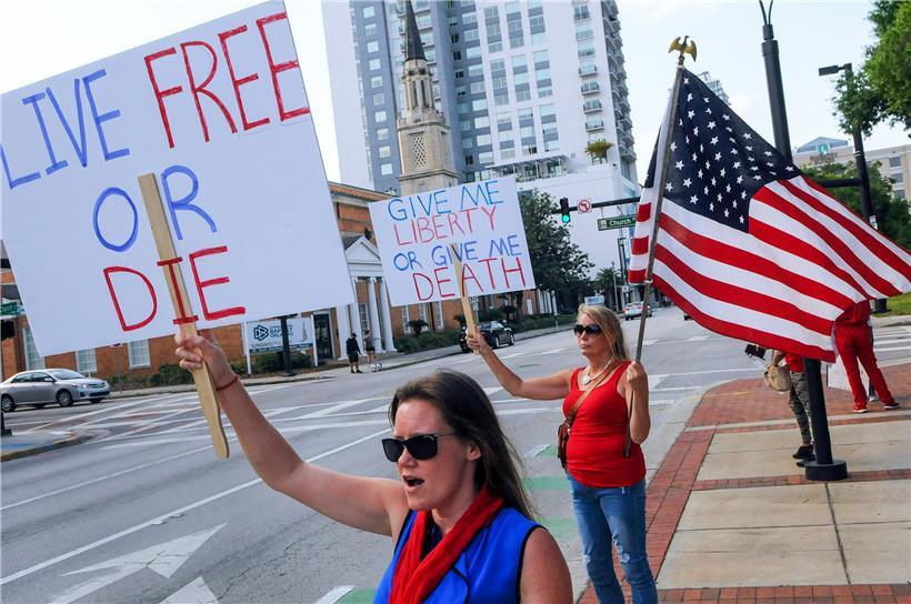 Demonstranten halten Schilder mit den Aufschriften „Live Free or Die“ (Lebe frei oder strib) und „Give me liberty or give me Death“ (Gib mir Freiheit oder gib mir den Tod) bei einem Proteste gegen die Ausgangsbeschränkungen aufgrund des neuartigen Coronavirus. 
