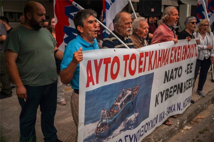 Demonstranten mit einem ein Banner, auf dem steht: „Sie sind dieses Verbrechens ...