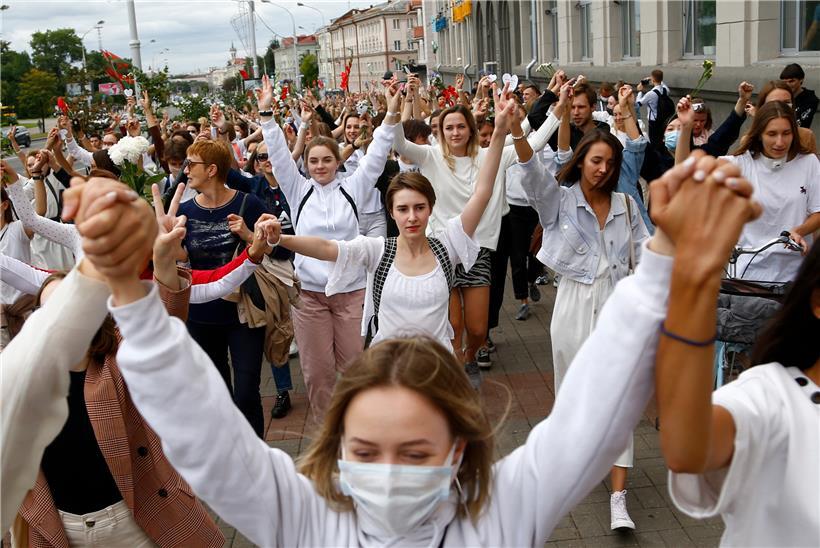 Demonstrantinnen in weißer Kleidung machen Peace-Zeichen mit den Händen und halten Blumen und protestieren in Solidarität mit den Demonstranten, die bei den Protesten gegen Wahlfälschungen verletzt wurden
