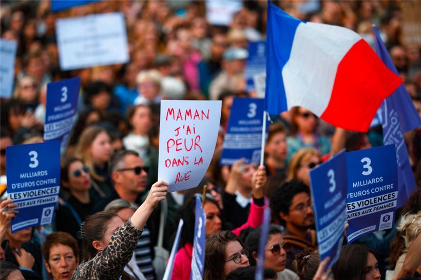 Demonstrierende zeigen Plakate, darunter eines mit der Aufschrift „Mama, ich habe Angst auf der Straße“, während eine andere Teilnehmerin der Demonstration eine französische Flagge schwenkt
