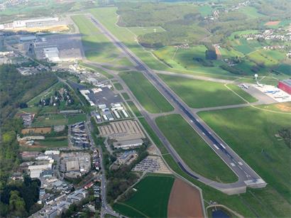 Vogelperspektive auf belebten Flughafen mit startenden und landenden Flugzeugen, Terminalgebäuden und Rollbahnen