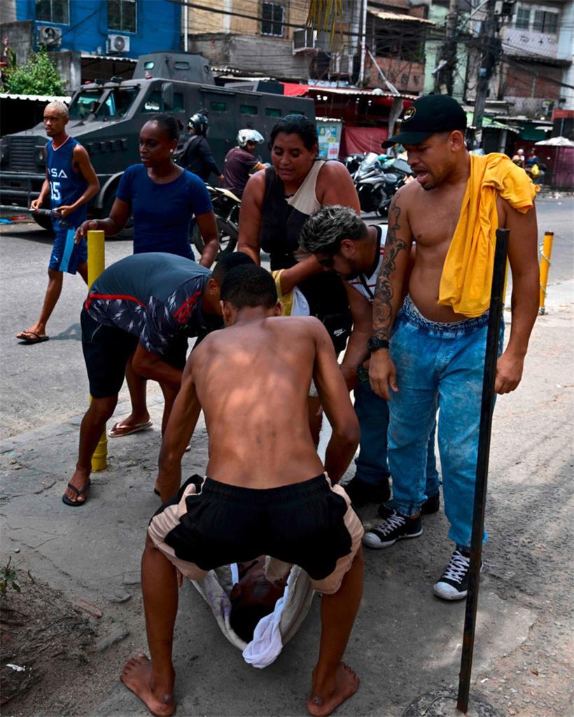 Der Leichnam eines in einer Schießerei zwischen Gangs und Polizei Getöteten wird weggetragen. Blutiger Alltag in der Favela Complexo de Alemão in Rio de Janeiro.
