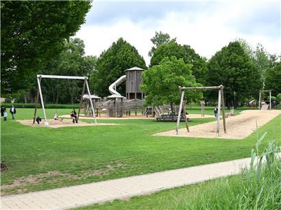 Sommerliche Parklandschaft im Merscher Park mit grünen Bäumen und entspannten Besuchern beim Erholen