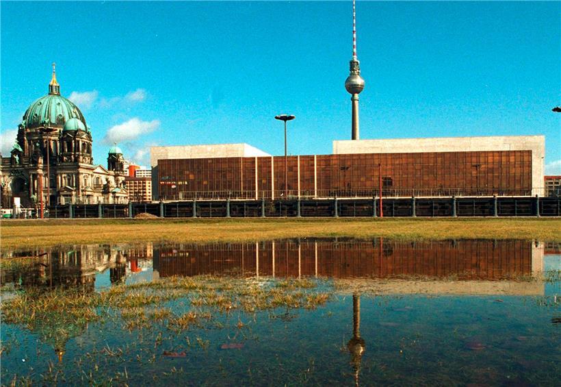 Der Palast der Republik in Berlin-Mitte spiegelt sich in einer großen Wasserlache, links steht der Berliner Dom und im Hintergrund der Fernsehturm
