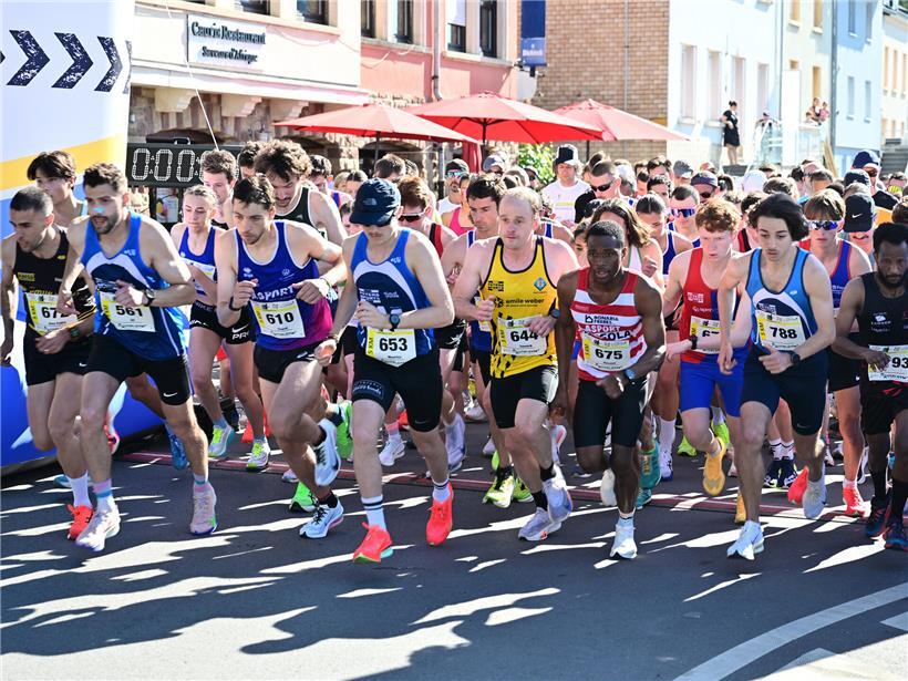 Start des Fünf-Kilometer-Rennens mit Läufern in Sportkleidung auf der Straße bei Wettkampfbeginn