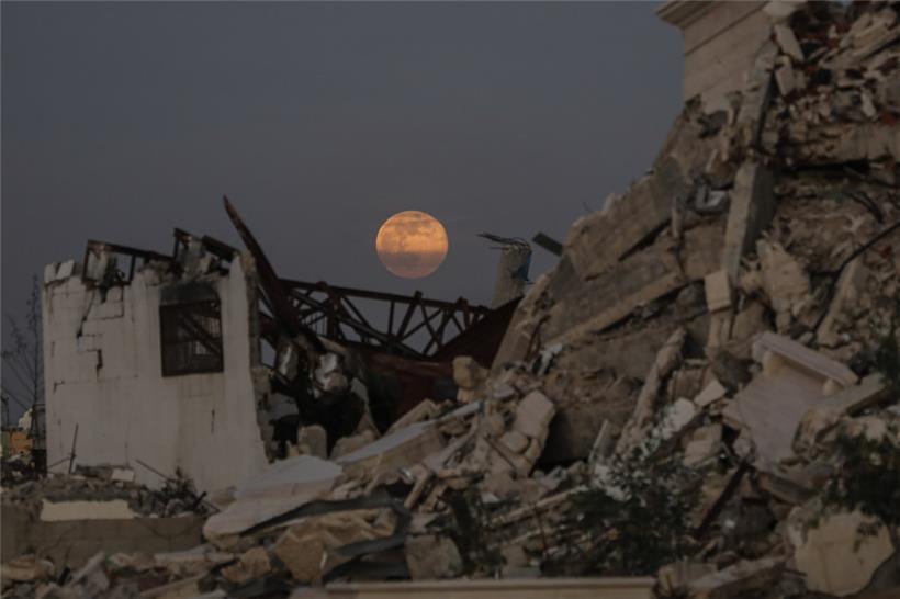 Der Vollmond geht am frühen Abend über zerstörten Gebäude im Zentrum des Gazastreifens auf
