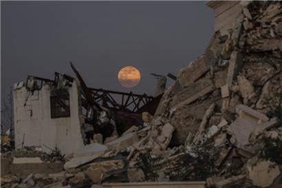 Der Vollmond geht am frühen Abend über zerstörten Gebäude im Zentrum des Gazastreifens auf
