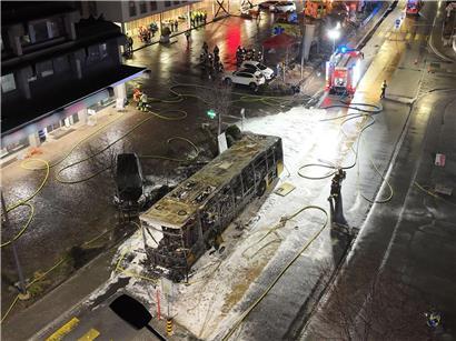 Ausgebrannter Bus in Kerzers, Westschweiz, auf städtischer Straße mit Rauch und Feuerwehr vor Ort