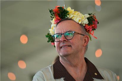 Der australische Premierminister Anthony Albanese trägt einen geblümten Kopfschmuck, während er mit dem Premierminister von Tuvalu Vereinbarungen über das Inkrafttreten der australisch-tuvaluischen Falepili-Union unterzeichnet
