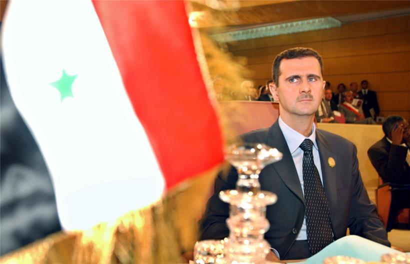 Der damalige syrische Präsident Baschar al-Assad blickt auf die Flagge seines Landes
