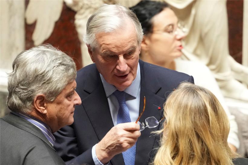 Der französische Premierminister Michel Barnier (M.) spricht mit Menschen in der Nationalversammlung
