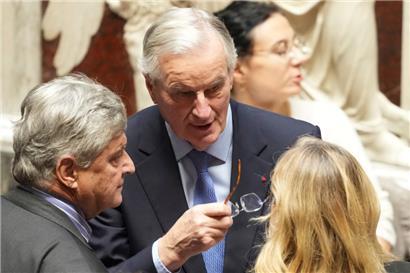 Der französische Premierminister Michel Barnier (M.) spricht mit Menschen in der Nationalversammlung
