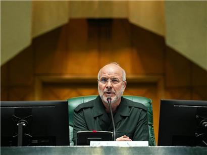 Mohammed Bagher Ghalibaf, iranischer Parlamentspräsident, in formeller Kleidung vor iranischer Flagge stehend